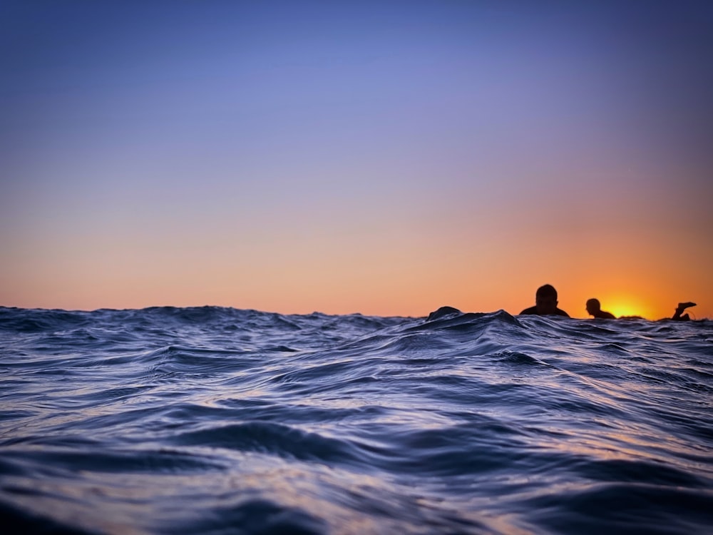 a person swimming in the ocean at sunset