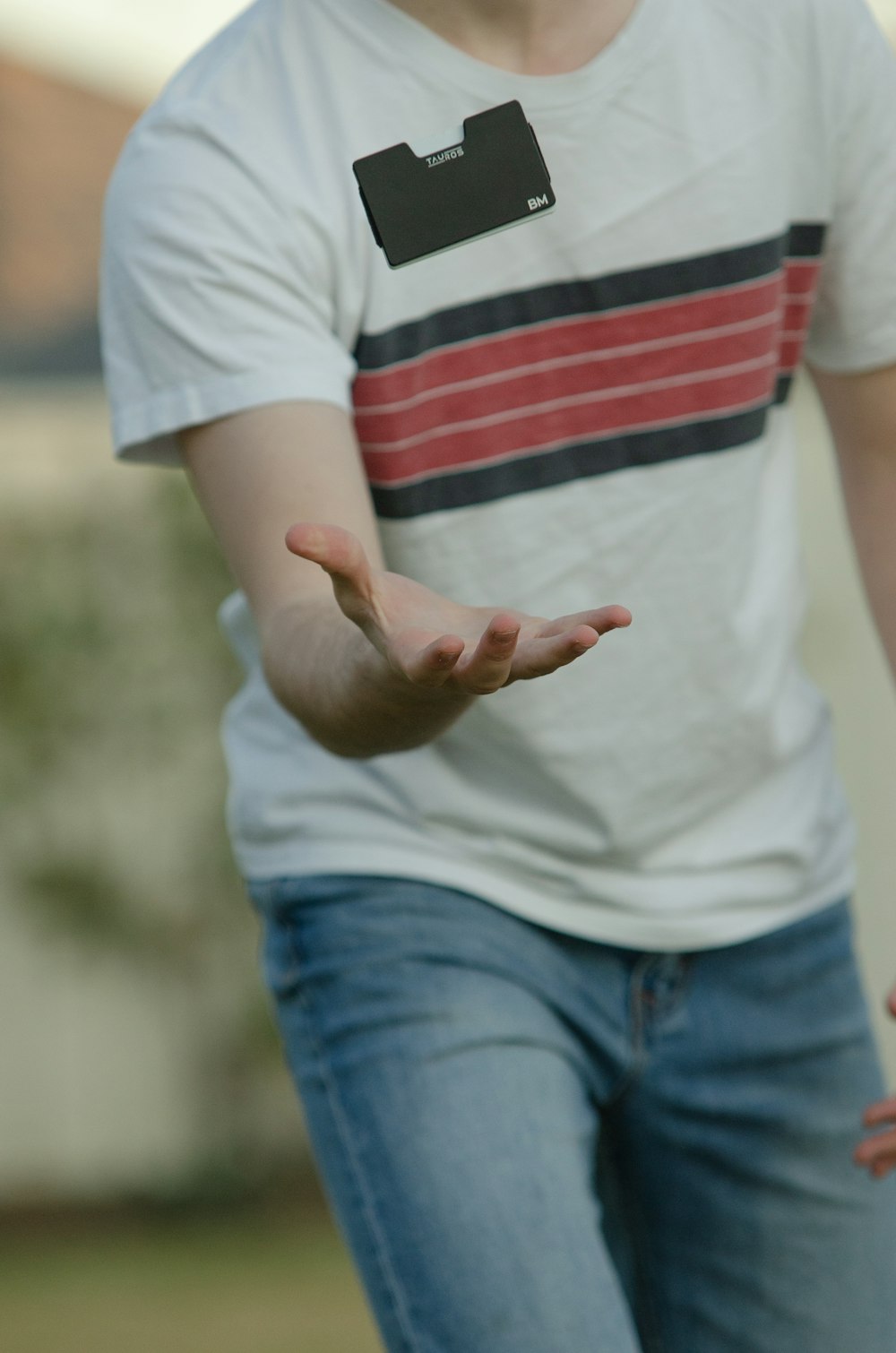 person in white red and black striped shirt and blue denim jeans