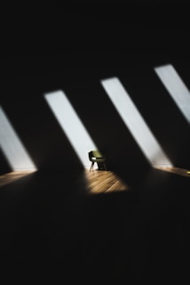 An empty white room with a single chair casting a long shadow.