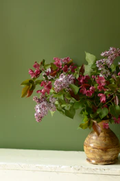 A beautifully arranged bouquet of fresh flowers in a rustic vase, set against a soft, natural backdrop.