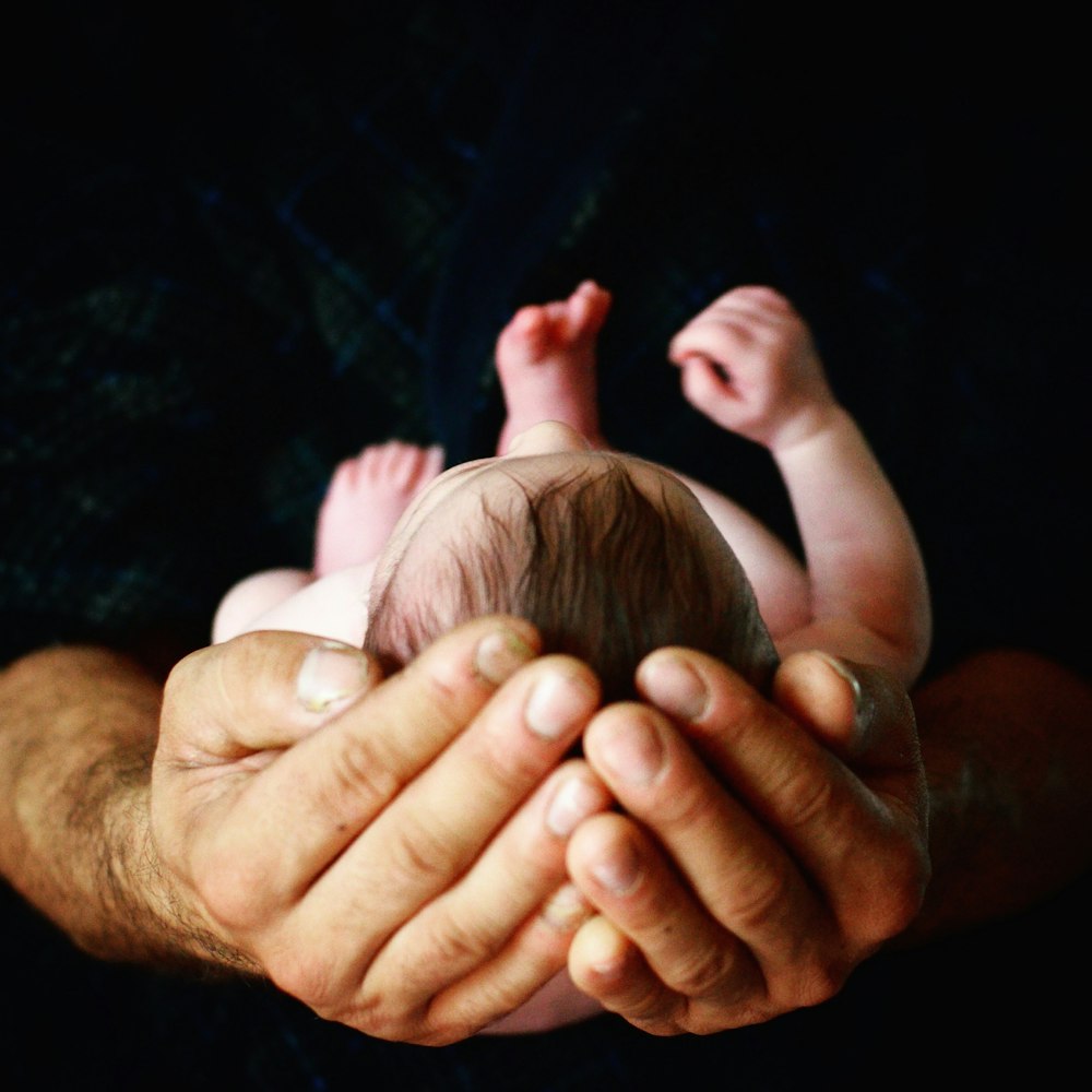 personne tenant la main du bébé