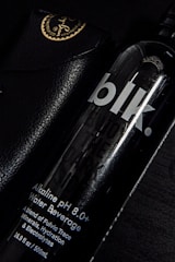 Close-up view of Platinapure 250ml bottled water with a sleek black and #b99a4c label under natural light.