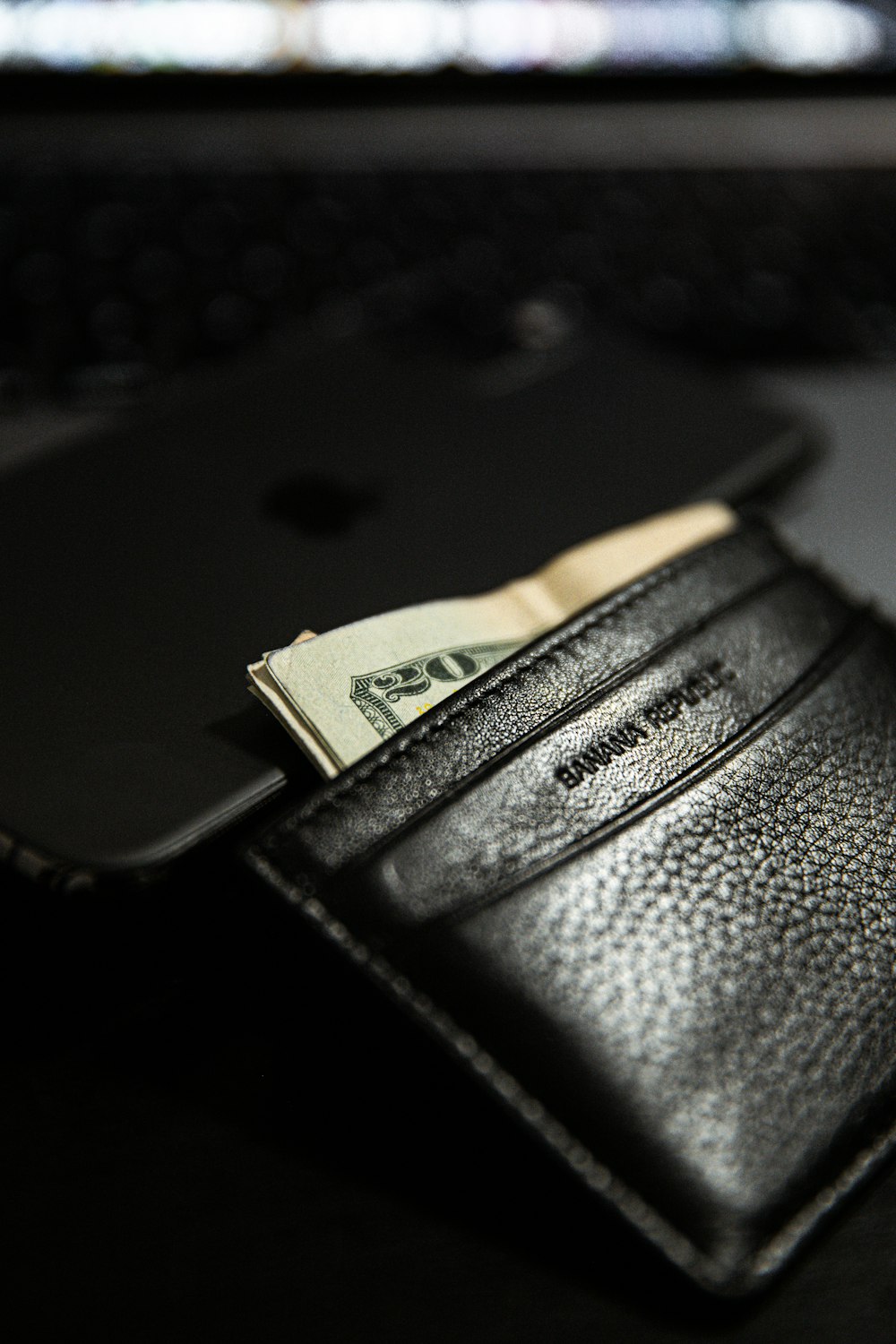 black leather bifold wallet on black laptop computer