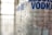 A close-up view of a clear glass bottle with the words 'ABSOLUT VODKA' prominently displayed in bold blue letters. The bottle features elegant, scripted black text detailing its craftsmanship, origin in Åhus, Sweden, and the year 1879. The background is softly blurred, giving emphasis to the bottle.
