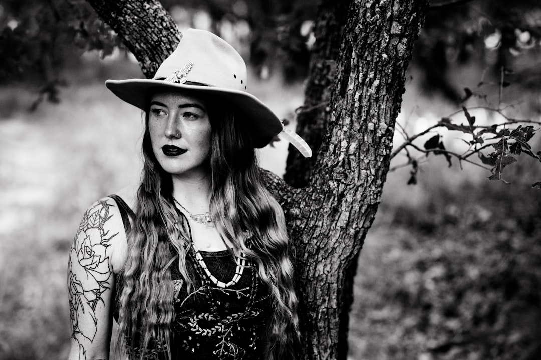 woman in black and white tank top wearing white hat standing beside tree