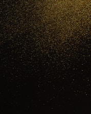 Abstract gold texture shimmering against a dark, obsidian background.