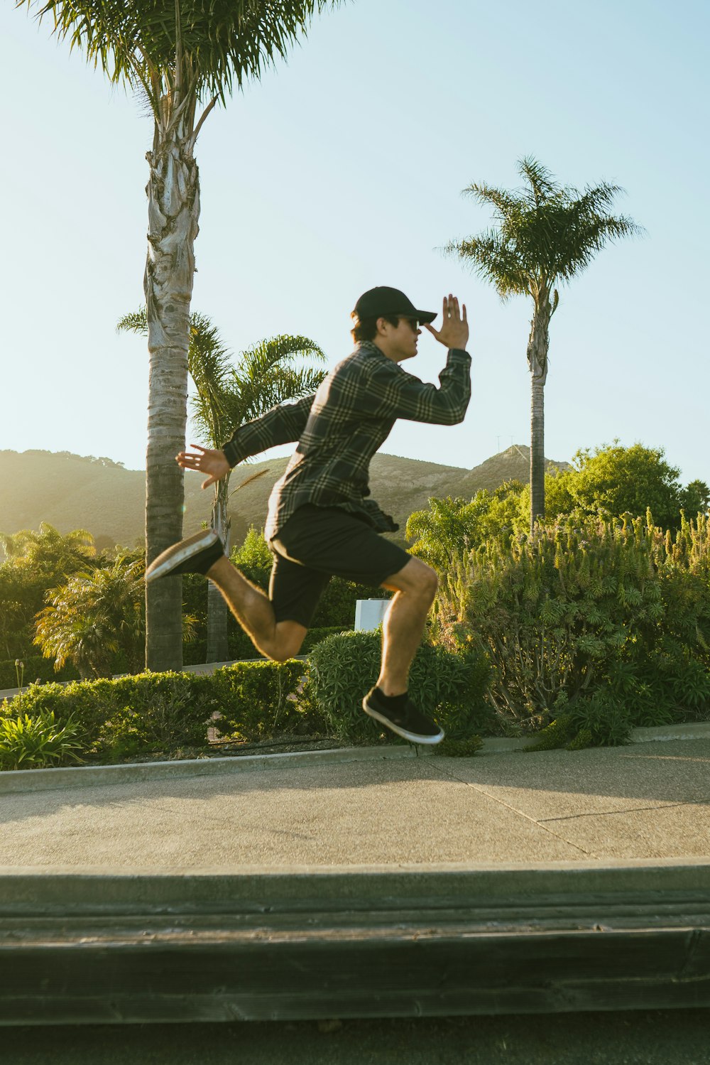 Hombre con camisa negra y pantalones cortos negros saltando en un camino de concreto gris durante el día