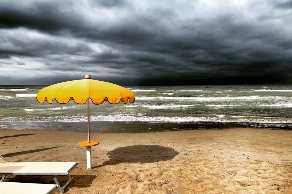 Orangefarbener Sonnenschirm am Strand tagsüber