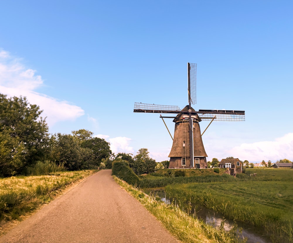 Braune Windmühle auf grünem Grasfeld unter blauem Himmel tagsüber