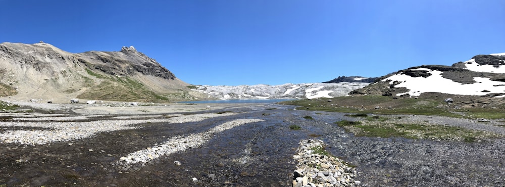 campo coperto di neve e montagne sotto il cielo blu durante il giorno