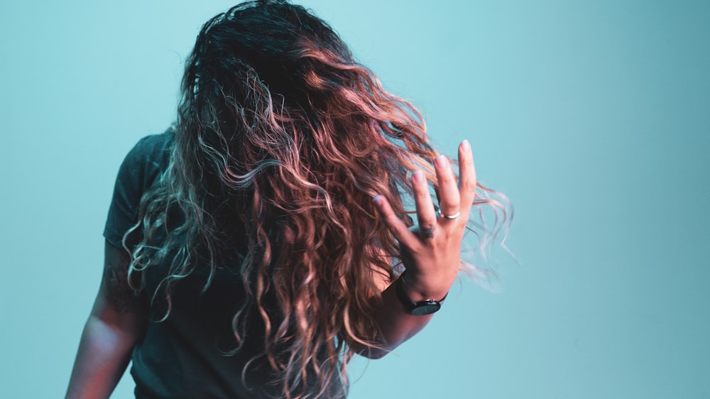 mulher na camisa preta cobrindo seu rosto com o cabelo