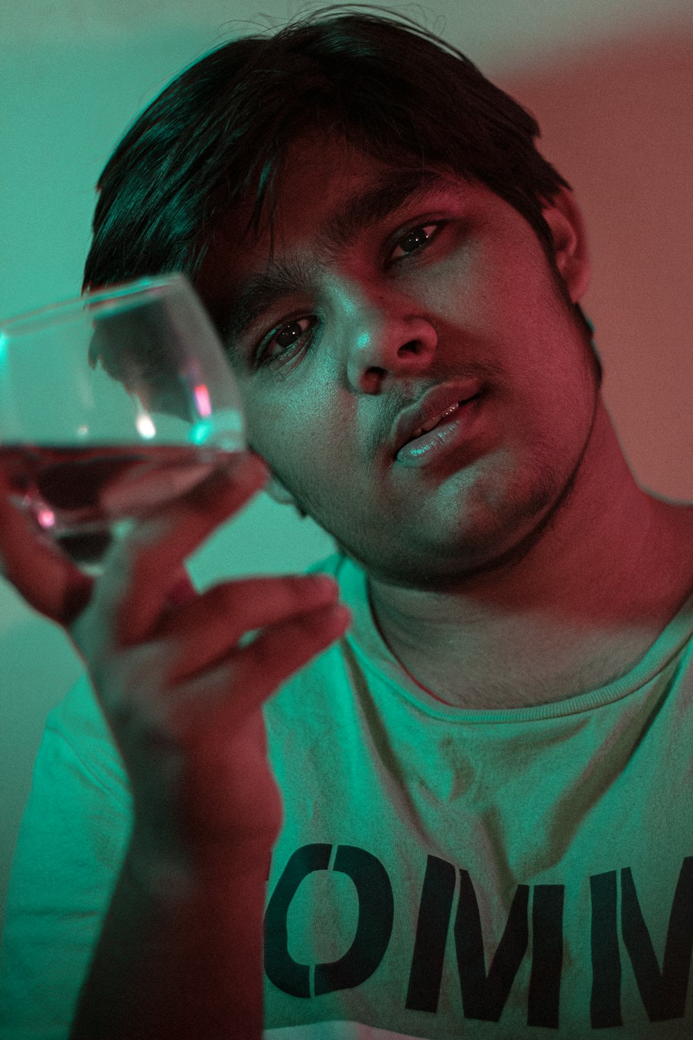 hombre con camisa verde de cuello redondo sosteniendo un vaso transparente para beber