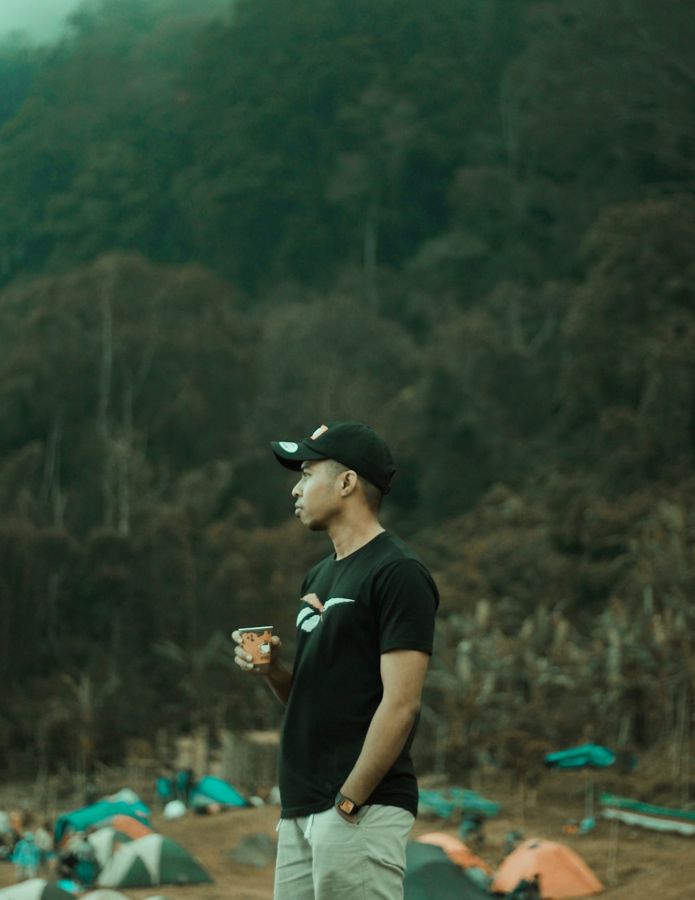 man in black crew neck t-shirt and black cap holding brown and black dslr camera