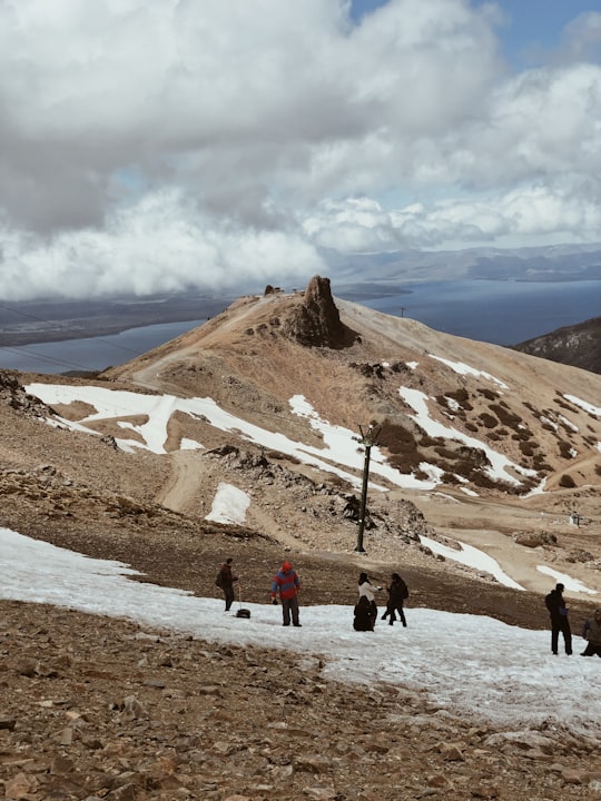 people walking on brown field near brown mountain under white clouds during daytime in Cerro Catedral Argentina