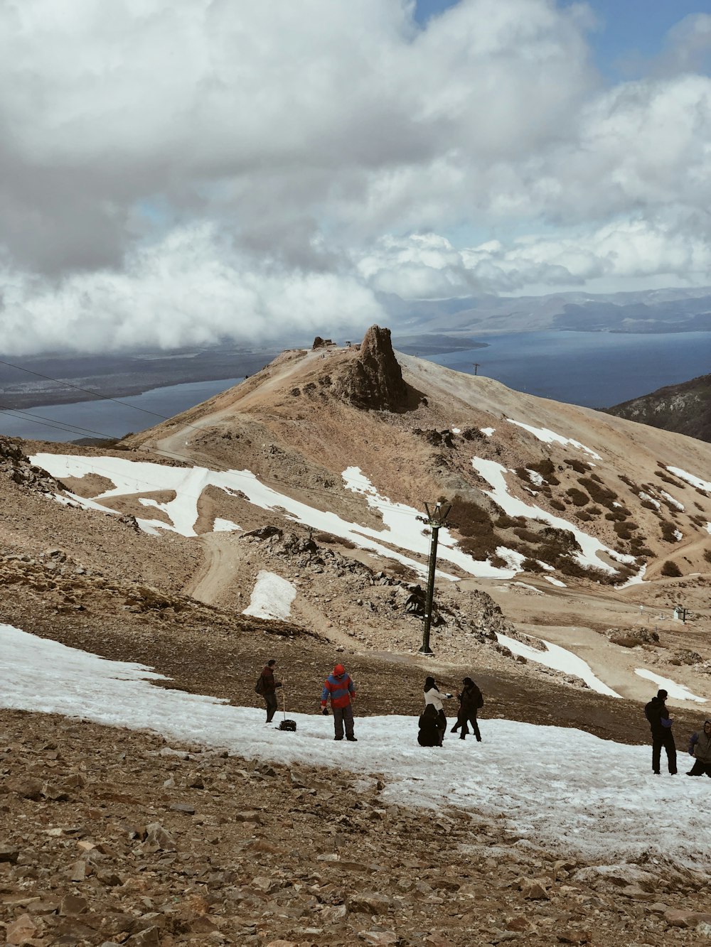 people walking on brown field near brown mountain under white clouds during daytime