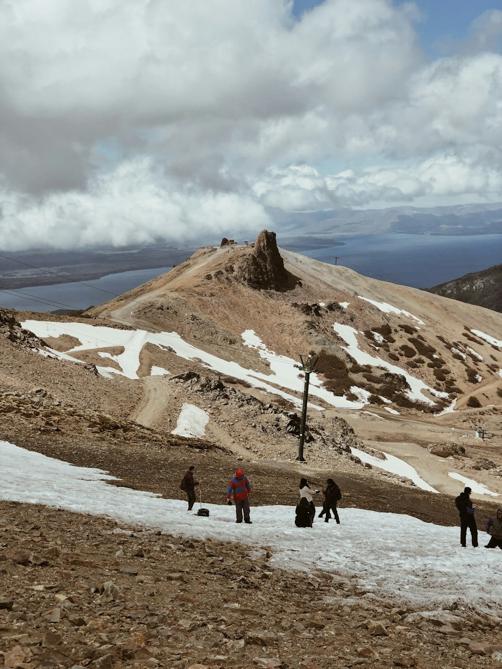 Persone che camminano sul campo marrone vicino alla montagna marrone sotto le nuvole bianche durante il giorno