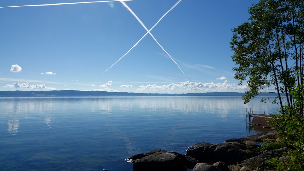 body of water near mountain under blue sky during daytime