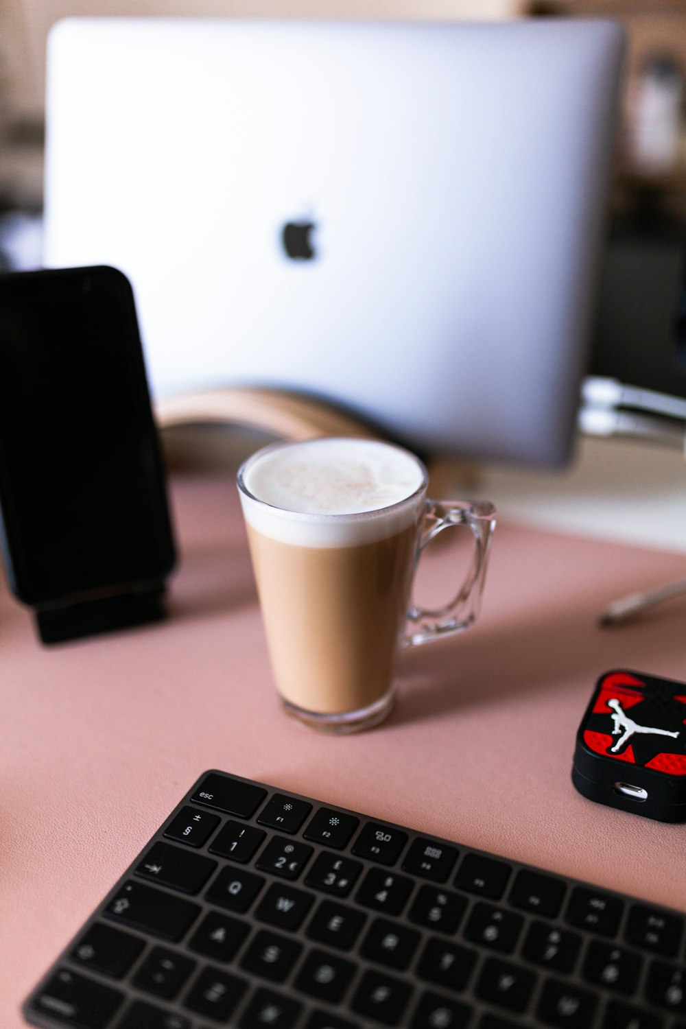 tazza in ceramica bianca accanto a smartphone nero su tavolo di legno marrone