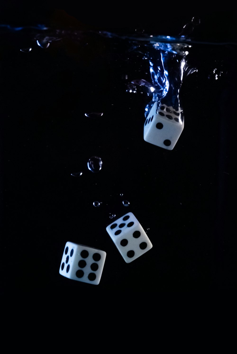three dices floating in the water on a black background