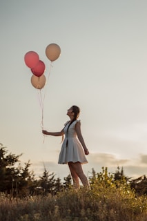 woman in blue and white dress holding balloons