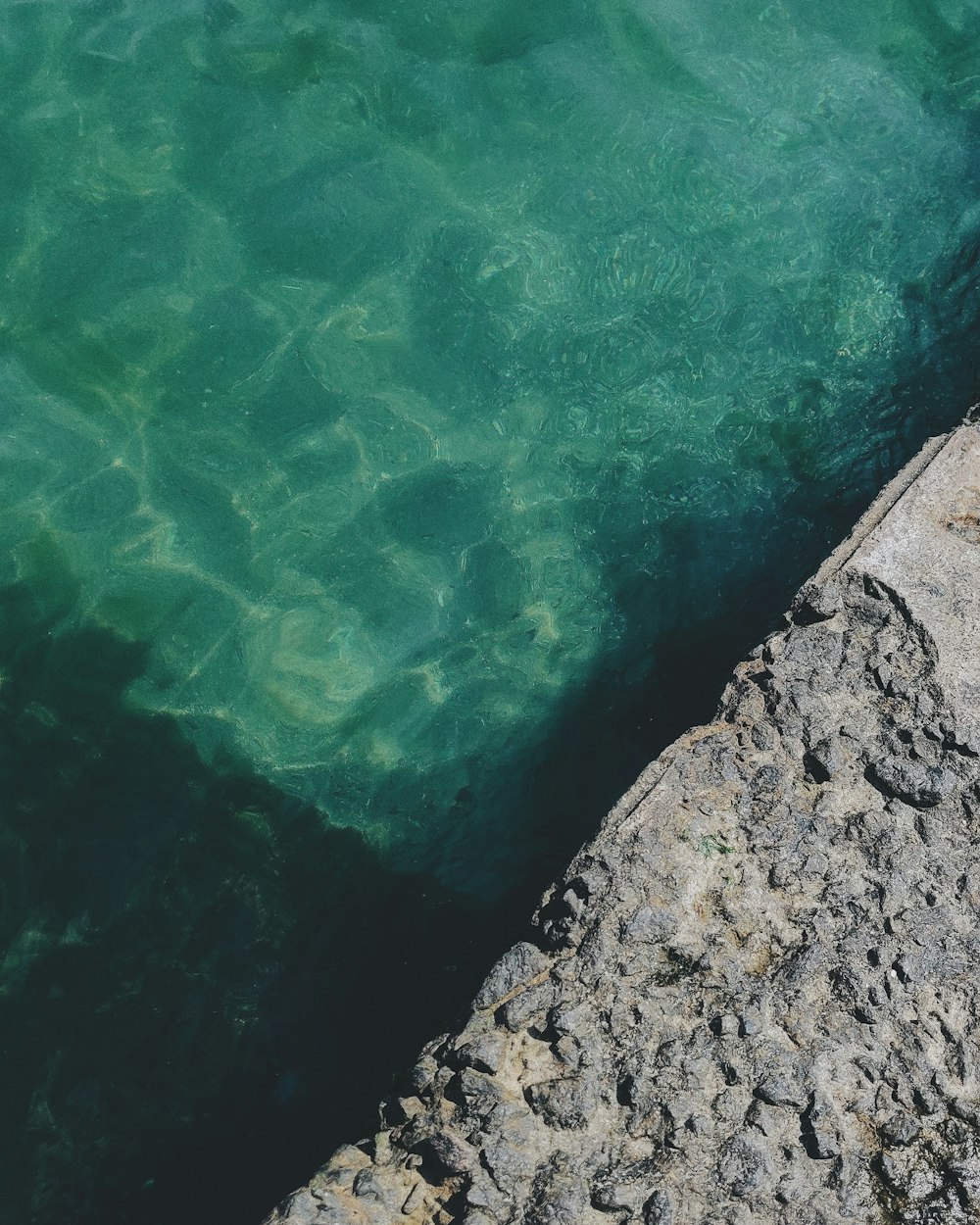 gray concrete wall beside body of water during daytime