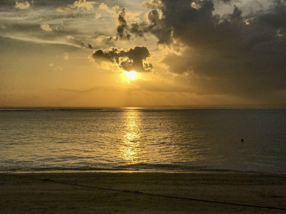 body of water under cloudy sky during sunset