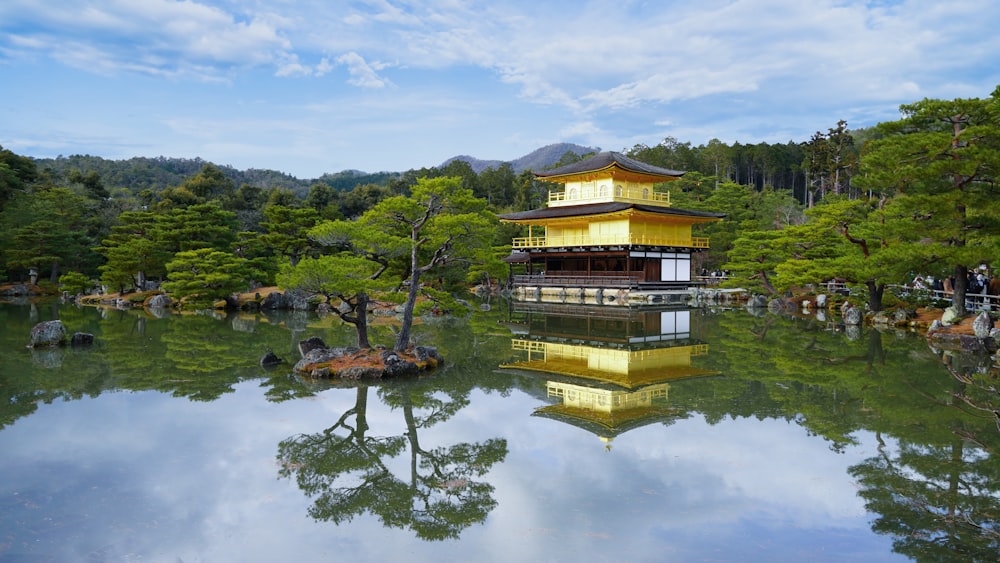 brown and green wooden house on green lake surrounded by green trees under white clouds and