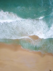 Aerial view of a serene beach with turquoise waves crashing.