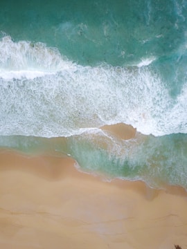 Aerial view of a serene beach with turquoise waves crashing.