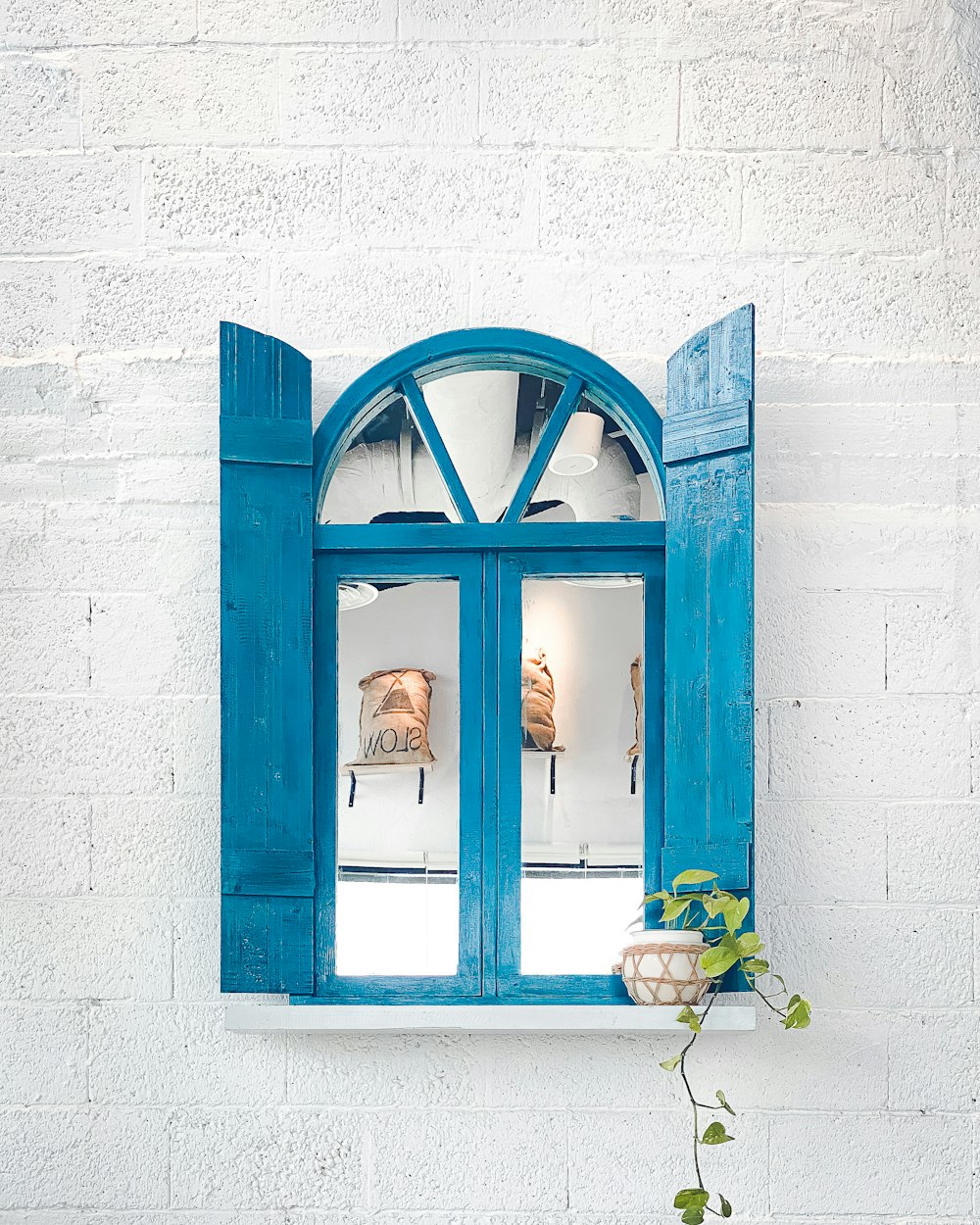 woman in black tank top standing in front of blue wooden window