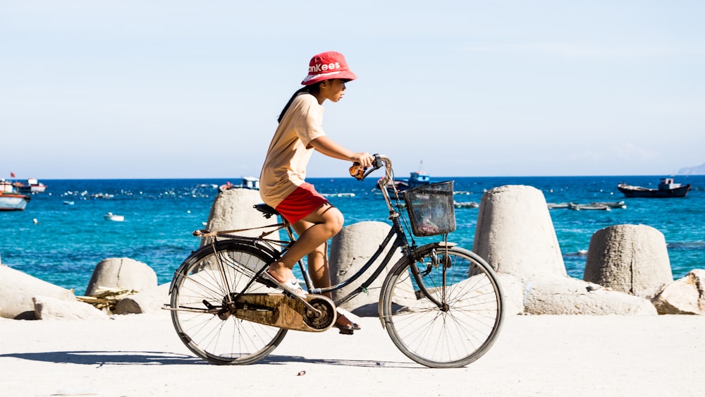 man in white shirt and blue shorts riding on blue city bicycle during daytime