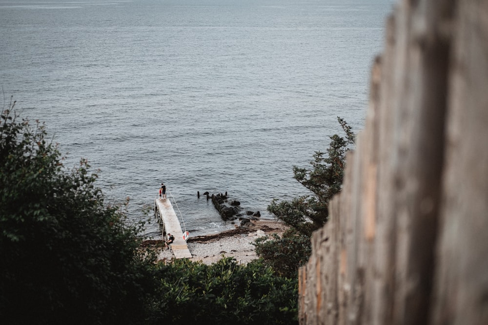 person in white shirt standing on brown concrete wall near body of water during daytime