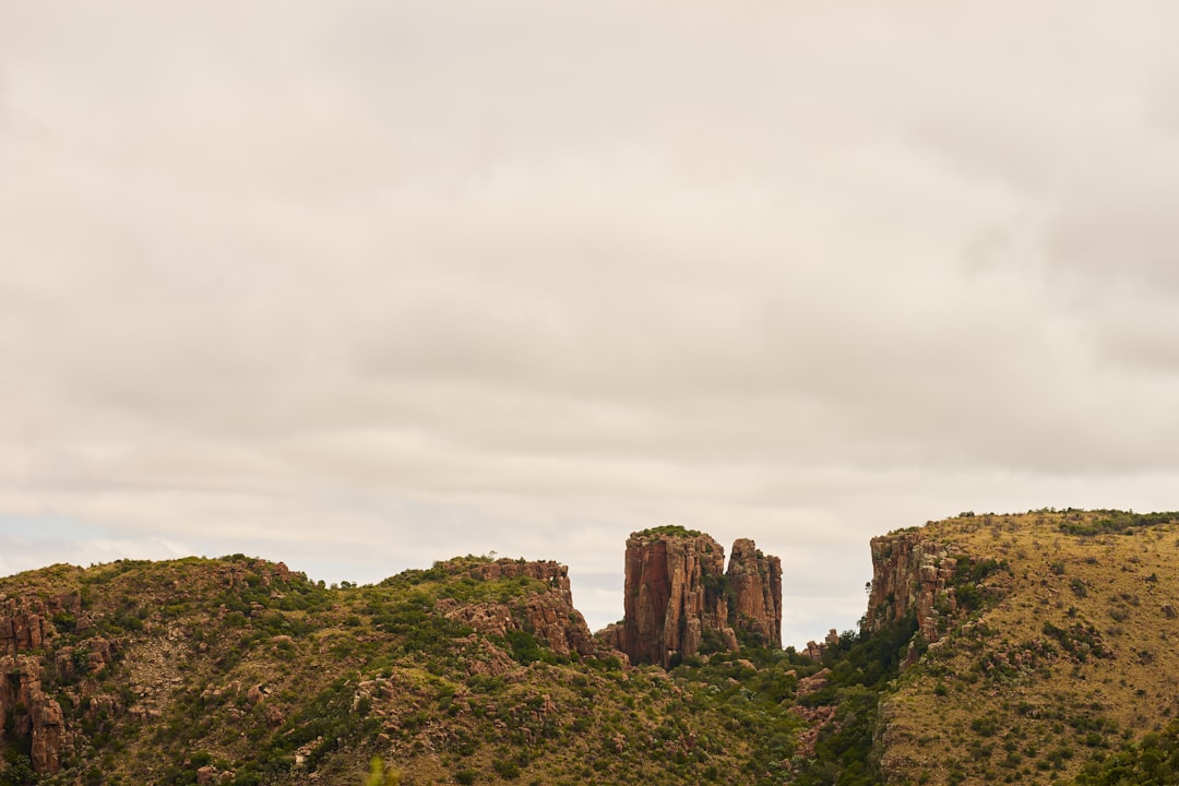 brown rock formation on green grass field under white cloudy sky during daytime