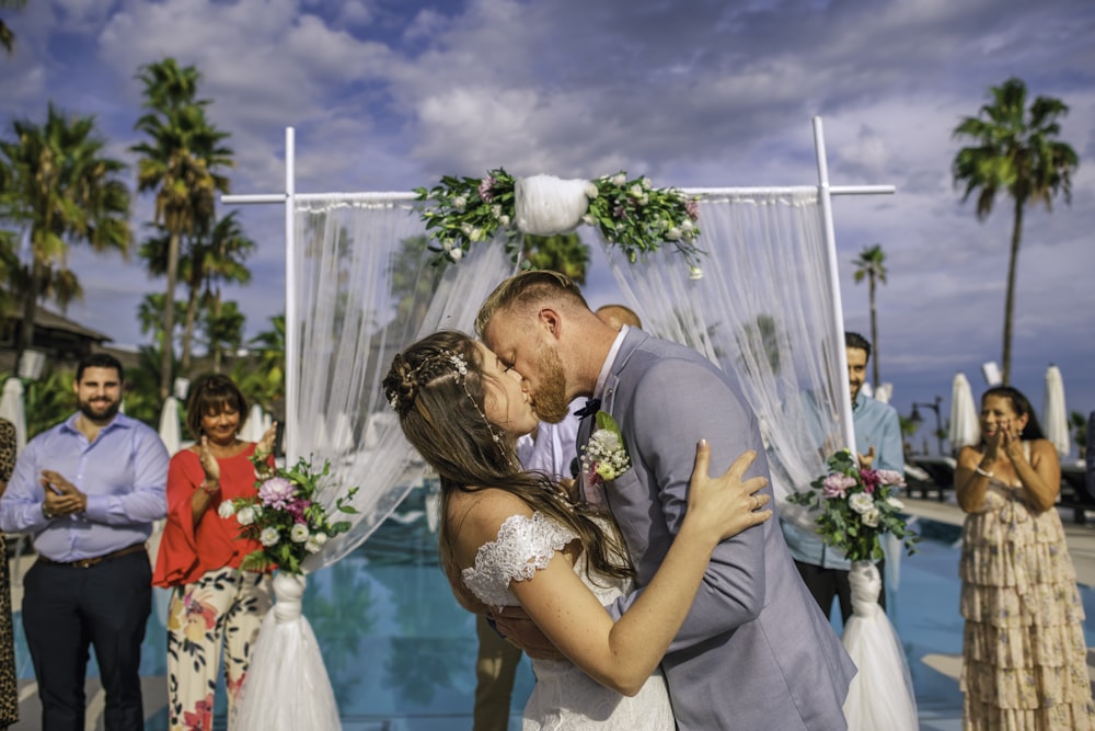 man in gray suit kissing woman in white wedding dress