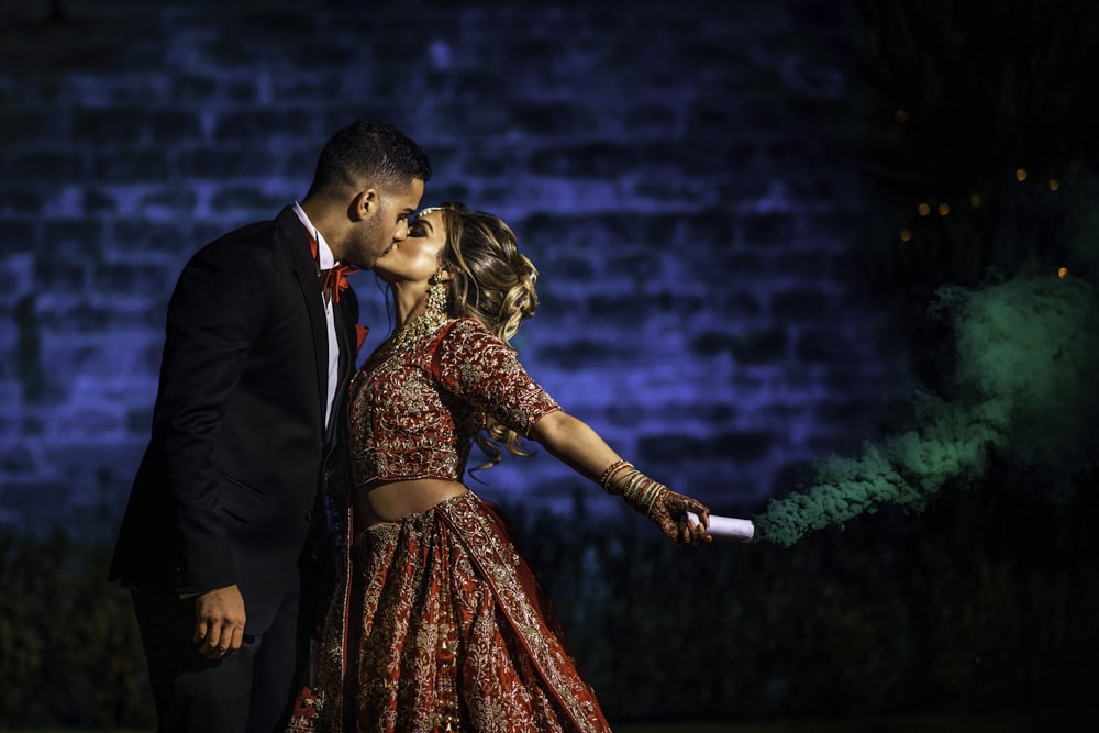 man in black suit jacket holding woman in red dress