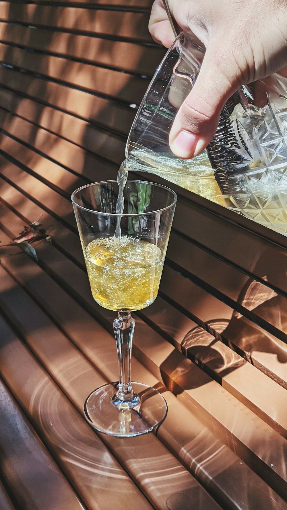 person holding clear drinking glass with yellow liquid