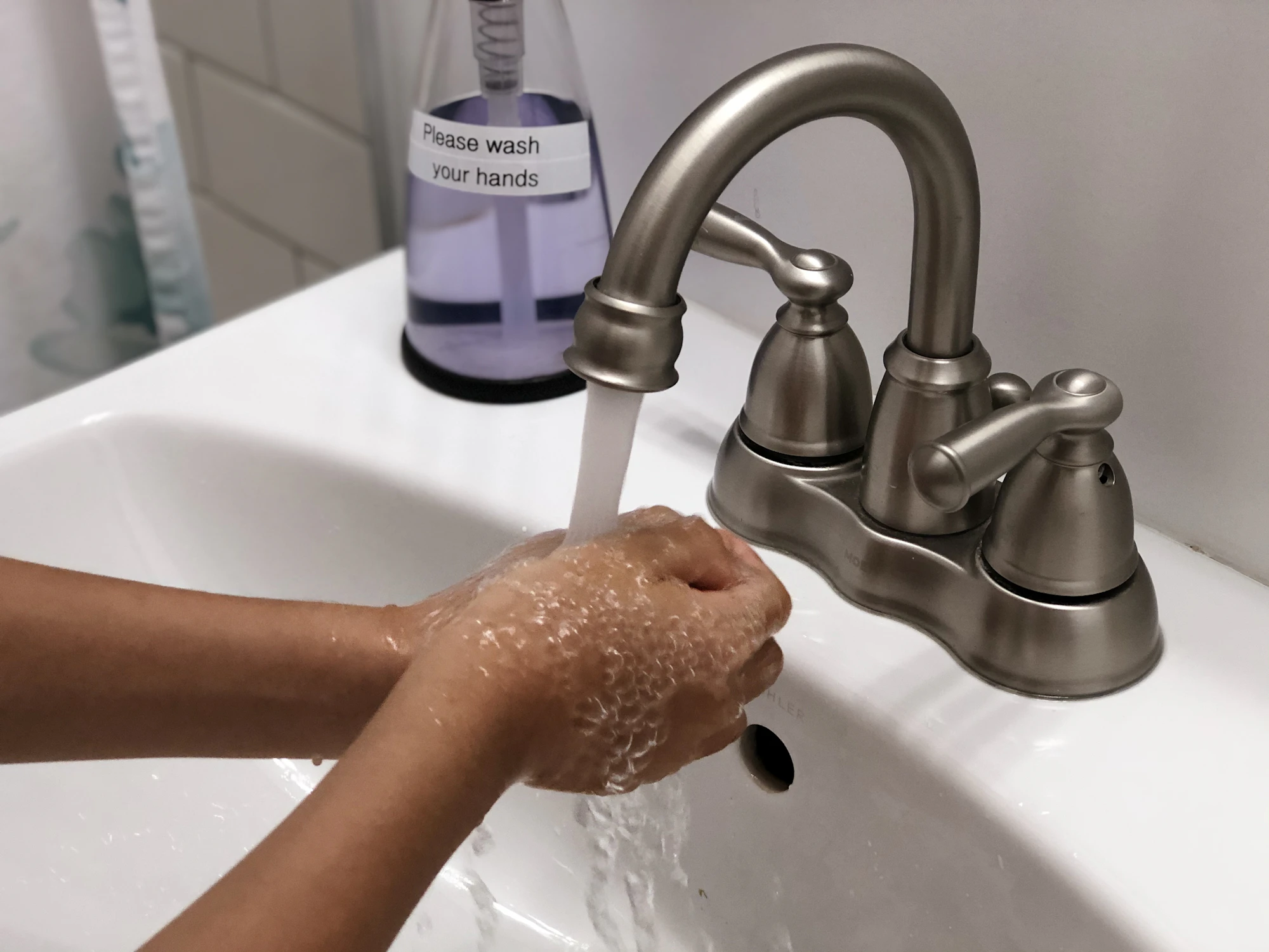 Hands lathered with soap under running water at a clean basin
