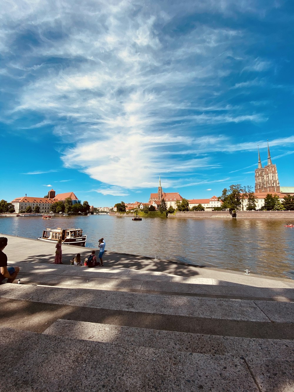 people sitting on concrete bench near body of water during daytime