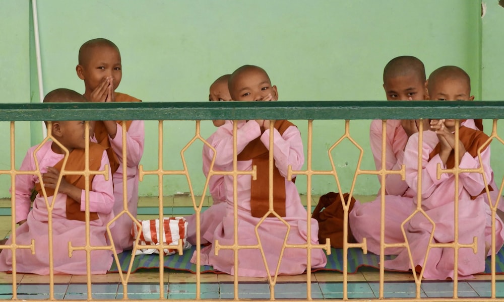 three baby in pink shirt on white metal frame