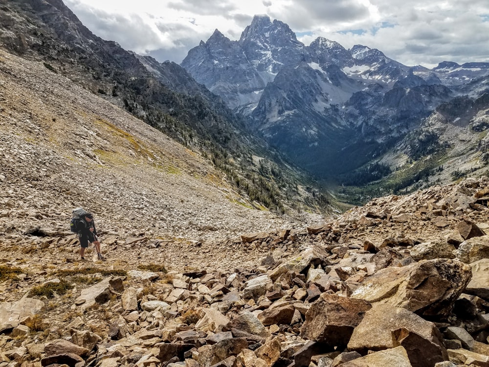 person walking on rocky road near mountains during daytime