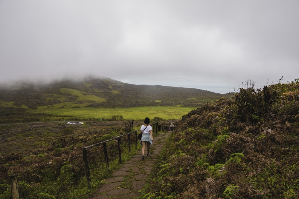 man in white shirt walking on brown wooden pathway