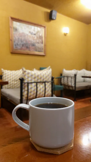 A cozy morning scene with a pastel pink ceramic mug filled with steaming coffee on a wooden table.