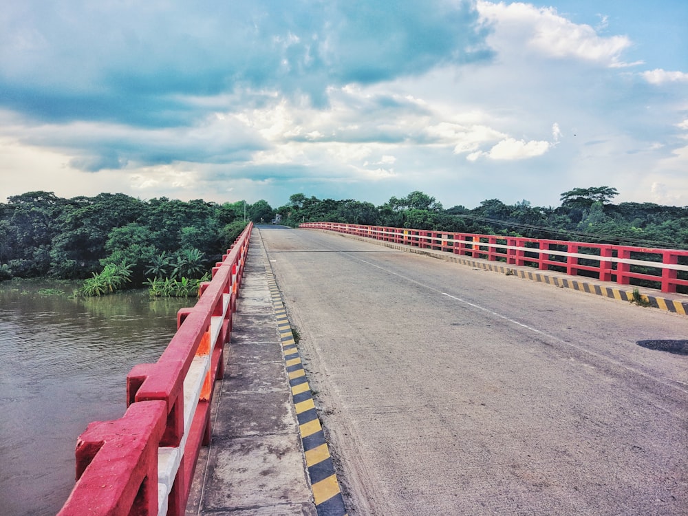 red and white road beside river under white clouds during daytime