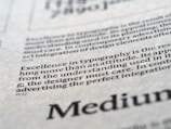 Close-up view of printed text on a textured paper surface. The focus is on the sentence 'Excellence in typography is the result of nothing more than an attitude.' The typeface and layout suggest a refined attention to typographic detail.