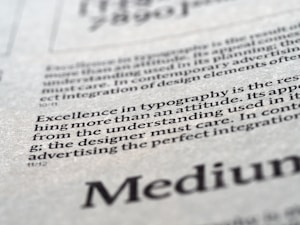 Close-up view of printed text on a textured paper surface. The focus is on the sentence 'Excellence in typography is the result of nothing more than an attitude.' The typeface and layout suggest a refined attention to typographic detail.