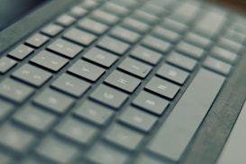 A close-up view of a computer keyboard, with keys featuring both Roman and possibly Cyrillic characters. The focus is shallow, drawing attention to specific keys while others appear blurred.