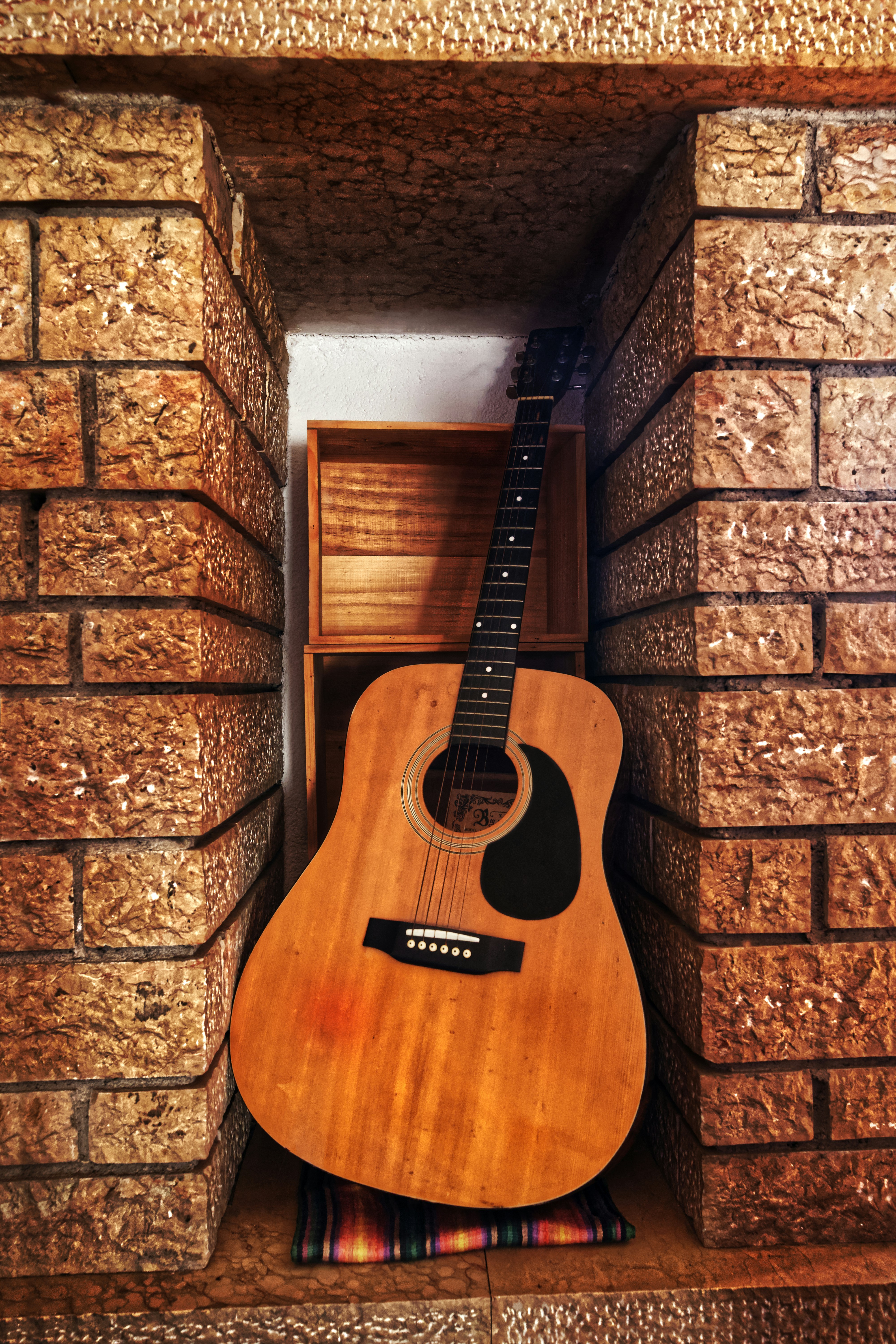 Chitarra acustica in piedi in una nicchia di mattoni.