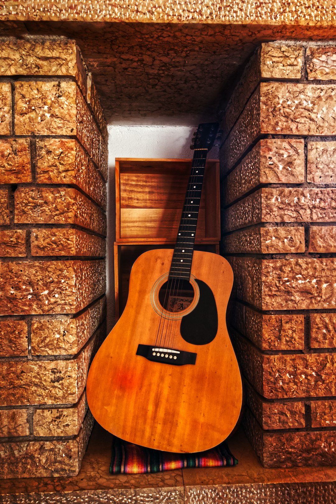 brown acoustic guitar on brown brick wall