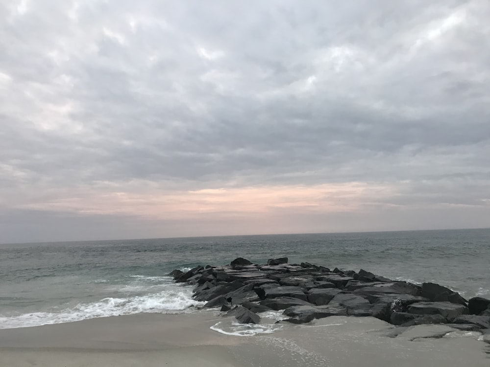 Schwarze Felsen an der Küste unter bewölktem Himmel tagsüber