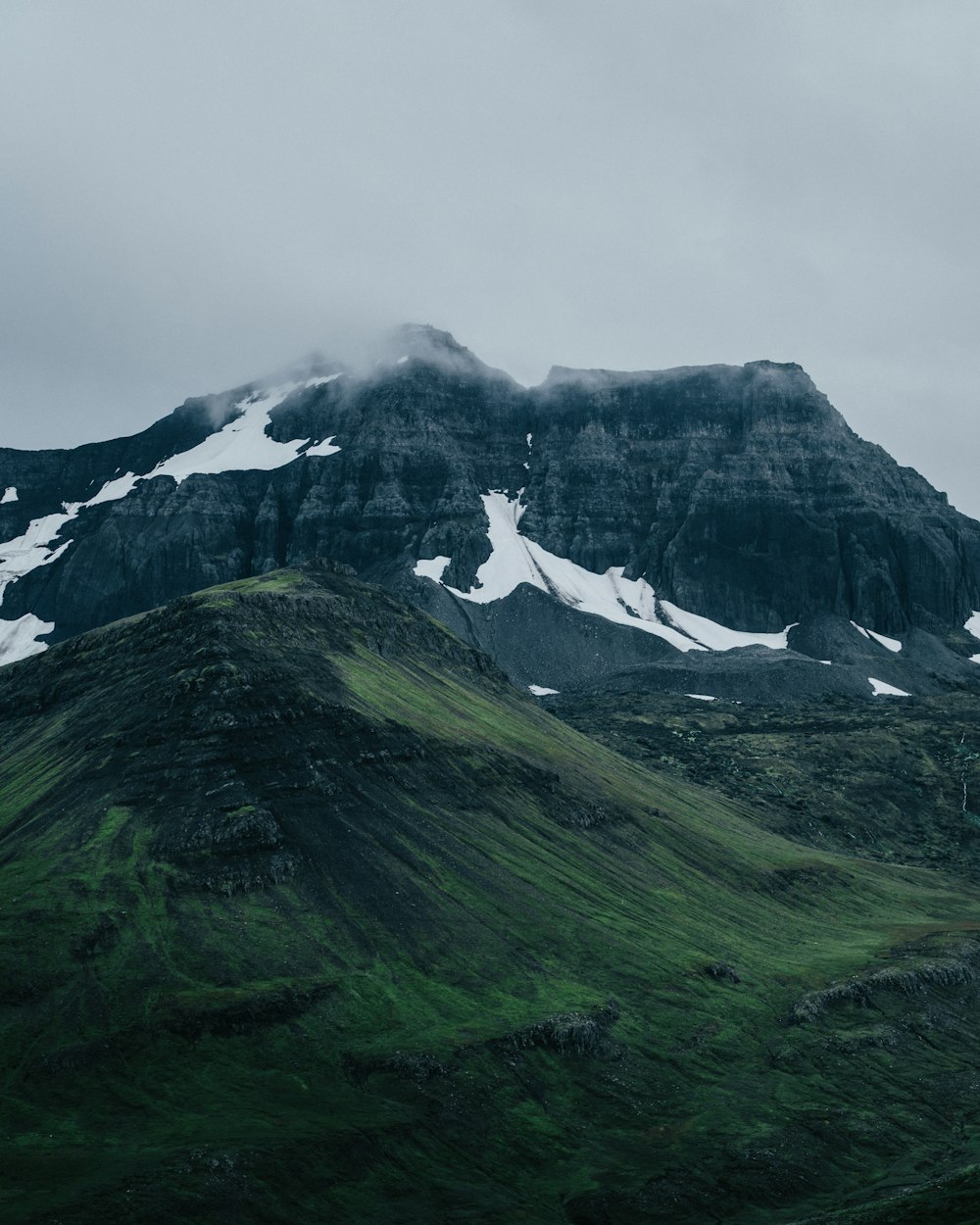 a mountain covered in snow and green grass